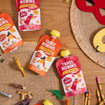 Three Robins Little Smoothie pouches on table surrounded by kids toy animals and dinosaurs, crayons and felt masks.
