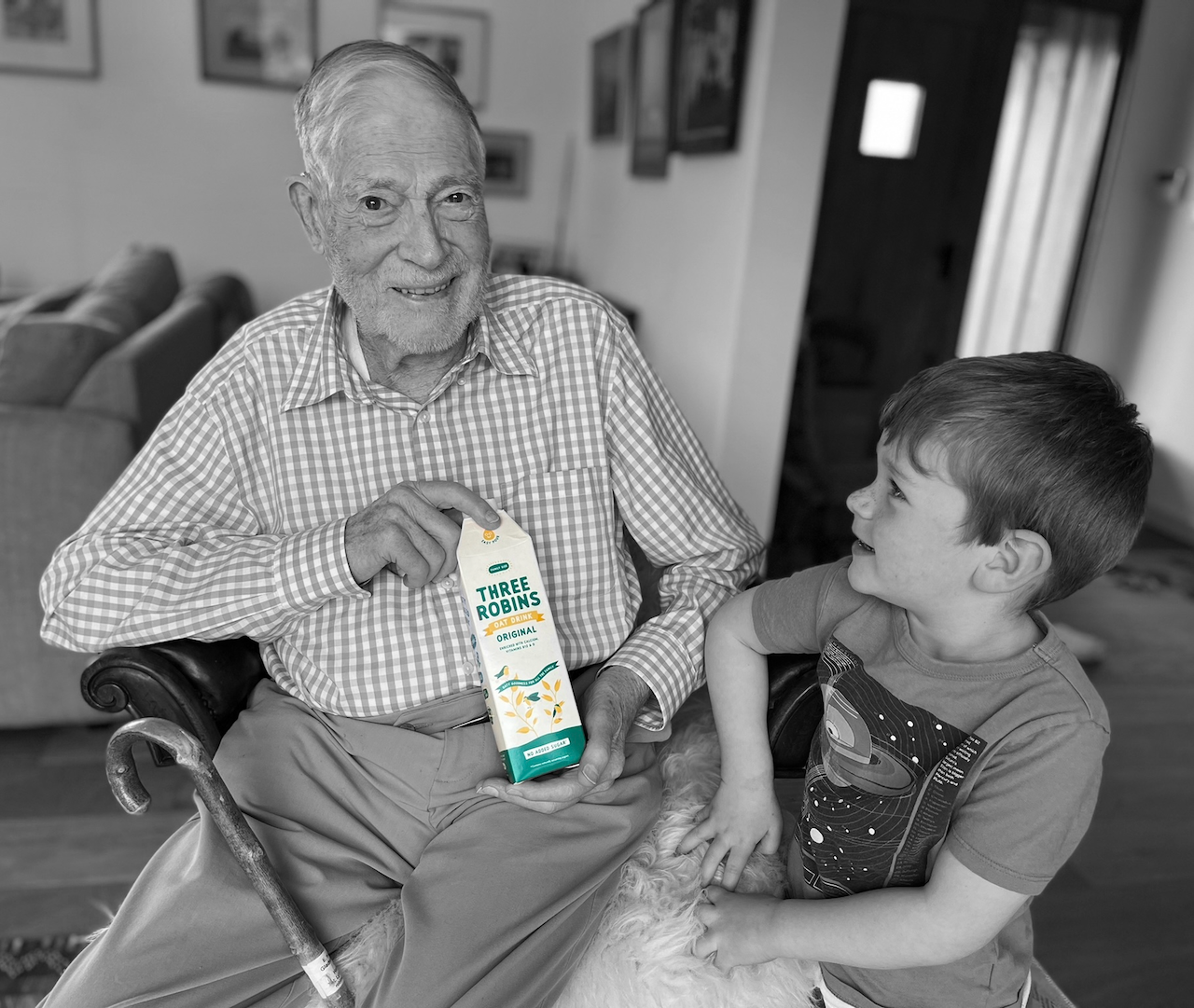 Great grandad holds carton of Three Robins Original Oat Drink while sitting with great grandson