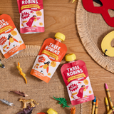 Three Robins Little Smoothie pouches on table surrounded by kids toy animals and dinosaurs, crayons and felt masks.