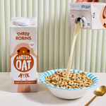 Three Robins barista oat milk carton beside a bowl of cereal with oat milk being poured in 